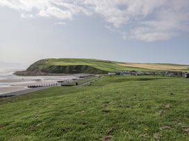 A beach with a hill and houses at Puffin in St Bees