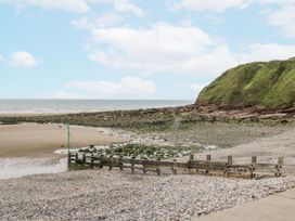 A beach with a cliff and water at Puffin in St Bees