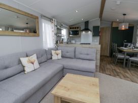 A living room with a sofa and kitchen area at Sandpiper in St Bees