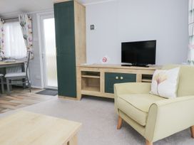 A living room with a television and dining table at Sandpiper in St Bees