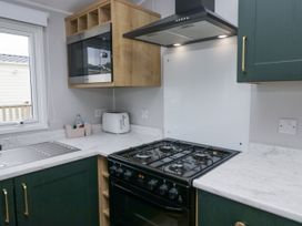 A kitchen with a gas stove and microwave at Sandpiper in St Bees