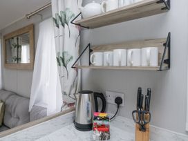 A kitchen with mugs on a shelf and a kettle at Sandpiper in St Bees