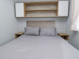 A bedroom with a bed and shelves at Sandpiper in St Bees