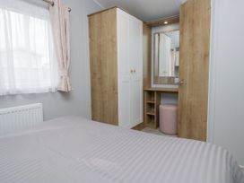 A bedroom with a wardrobe and mirror at Sandpiper in St Bees