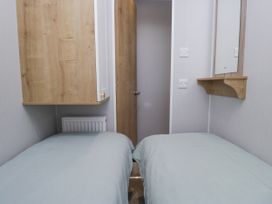 A bedroom with two beds and a cabinet at Sandpiper in St Bees
