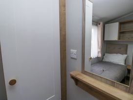 A bedroom with a bed and a mirror at Sandpiper in St Bees