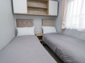 A bedroom with two single beds and a bedside table at Sandpiper in St Bees