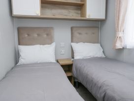 A bedroom with two single beds and a bedside table at Sandpiper in St Bees