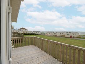 An outdoor area with a wooden deck and caravans at Sandpiper in St Bees