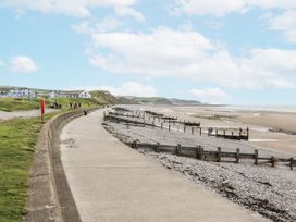 A beach view with a path and buildings at Sandpiper in St Bees