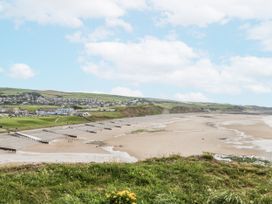 A beach scene with a pier and cliffs at Sandpiper in St Bees