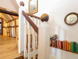A staircase with books on a shelf and a mirror in a hallway at Bank House