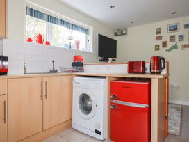 A kitchen with a washing machine and red refrigerator at Mini Mena St Austell