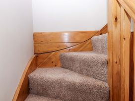 Stairs with carpet and wood railing at Church Barn in Sutcombe near Bradworthy