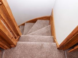 A staircase with carpet and wooden railing at Church Barn Sutcombe near Bradworthy