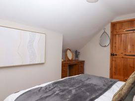 A bedroom with a bed and a dresser with a mirror at Church Barn in Sutcombe near Bradworthy