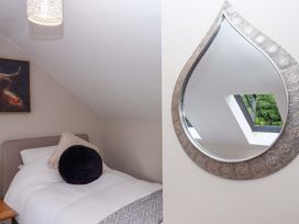 A bedroom with a bed, decorative pillow and mirror at Church Barn Sutcombe near Bradworthy