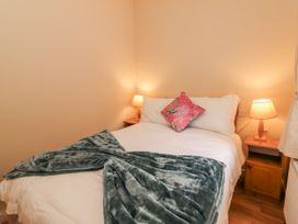 A bedroom with a bed and nightstands at Kate's Cottage