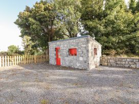 A stone building with a red door and window in an outdoor area at Kate's Cottage