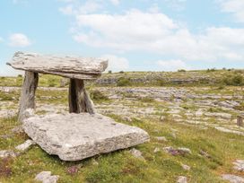 A stone table supported by pillars in a grassy landscape at Kate's Cottage