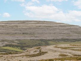 A landscape with hills and rocky surface under a blue sky at Kate's Cottage 