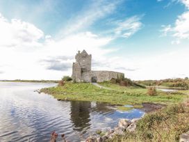 A castle near water with a path and grass at Kate's Cottage