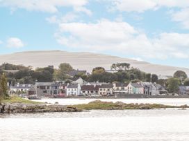 A view of houses along the water with a mountain in the background at Kate's Cottage