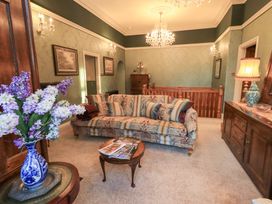 A living room with a sofa and chandelier at Summerlands Hall Apartment