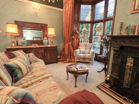 A living room with a sofa, armchair, and fireplace at Summerlands Hall Apartment