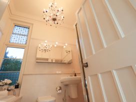 A bathroom featuring a chandelier, toilet, and sink at Summerlands Hall Apartment