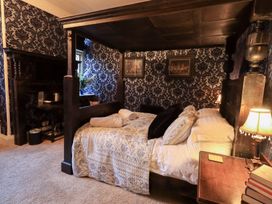 A bedroom with a four-poster bed and a bedside table at Summerlands Hall Apartment 