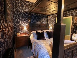 A bedroom with a four-poster bed and bedside table at Summerlands Hall Apartment