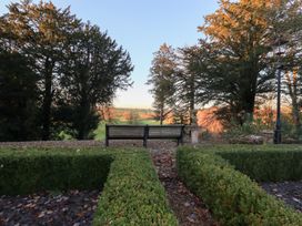 A view of a garden with a bench and trees at Summerlands Hall Apartment