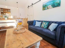 A living room with a blue sofa and wooden coffee table at Lavender Cottage
