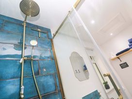 A bathroom with shower fixtures and towels at Lavender Cottage in 