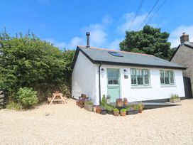 A cottage with a door and windows surrounded by plants and gravel at Lavender Cottage