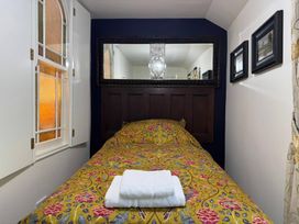 A bedroom with a bed and a mirror at St. James Cottage in Liskeard