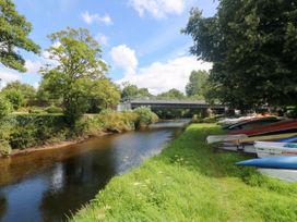 A river with a bridge and boats along the bank at St. James Cottage in St Cleer