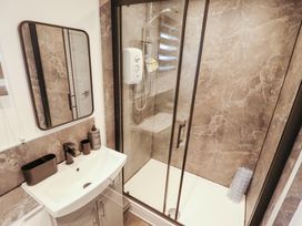 A bathroom with a shower, sink, and mirror at 66 Cherry Park Skegness