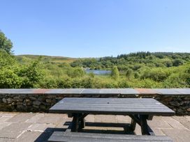 A picnic table with a view of a lake and surrounding hills at Ty Newydd