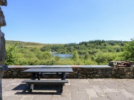 A table with benches overlooking a lake and trees at Ty Newydd