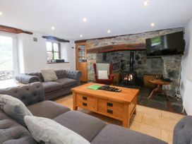 A living room with a fireplace and sofa at Ty Newydd Llanrhychwyn near Llanrwst
