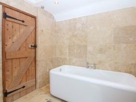 A bathroom with a bathtub and wooden door at Ty Newydd in Llanrhychwyn near Llanrwst