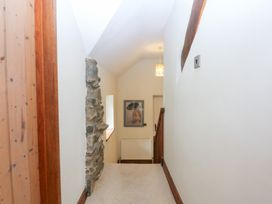 A hallway with a staircase and artwork at Ty Newydd Llanrhychwyn near Llanrwst