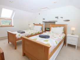 A bedroom with two beds and a window at Ty Newydd Llanrhychwyn near Llanrwst