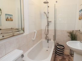 A bathroom with a bathtub, shower and sink at King Arthur Suite in Trearddur Bay