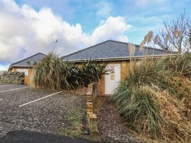 A building exterior with plants and parking area at King Arthur Suite in Trearddur Bay