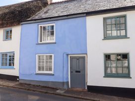 An exterior view of a house with a blue wall and gray door at Carpenters Cottage in Okehampton