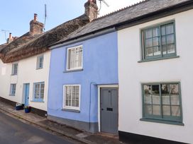 A blue and white house with a thatched roof at Carpenters Cottage Okehampton