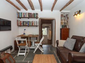 A living room with bookshelves and a table at Carpenters Cottage Okehampton